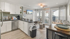 Una cucina moderna con mobili bianchi, lavastoviglie e zona pranzo con tavolo e sedie.