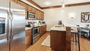 Una cocina moderna con electrodomésticos de acero inoxidable, armarios de madera y encimera de mármol.