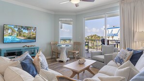 A living room with a TV, a ceiling fan, a poolside view, and a balcony with a 'Island' sign.