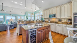 A spacious kitchen with a large island, wooden cabinets, and a built-in wine cooler. - Premier Oceanfront Dog Friendly w/ Pool, Hot Tub, Elevator, Theater and Game Rms (Rodanthe)
