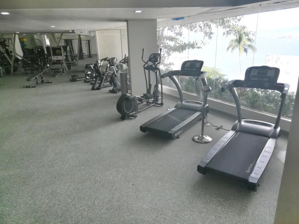 Ein Fitnessstudio mit Laufbändern, Crosstrainern und Gewichten.