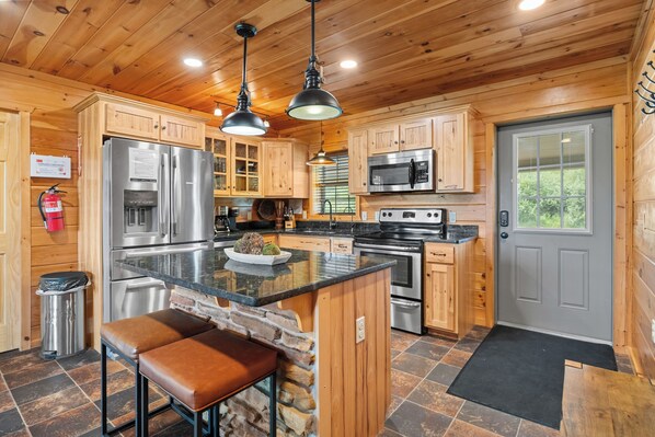 A modern kitchen with wooden cabinets, stainless steel appliances, and a stone accent wall.