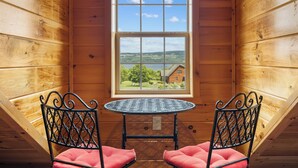 Una pequeña habitación de madera con ventana, dos sillas y una mesa.