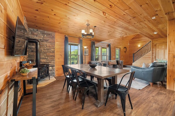 A wooden interior with a dining table, chairs, a fireplace, and a staircase. - Castello at Castle Point, 3 bedroom cabin with hot tub, pool table, lake view! (Himrod)