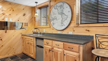 A kitchen with wooden cabinets, a granite countertop, a sink, and a large wall map.