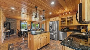 A spacious kitchen with wooden cabinets, a stainless steel refrigerator, and a granite countertop.