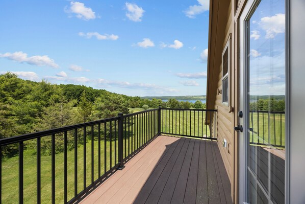 Un balcon donnant sur un paysage verdoyant et un ciel dégagé.
