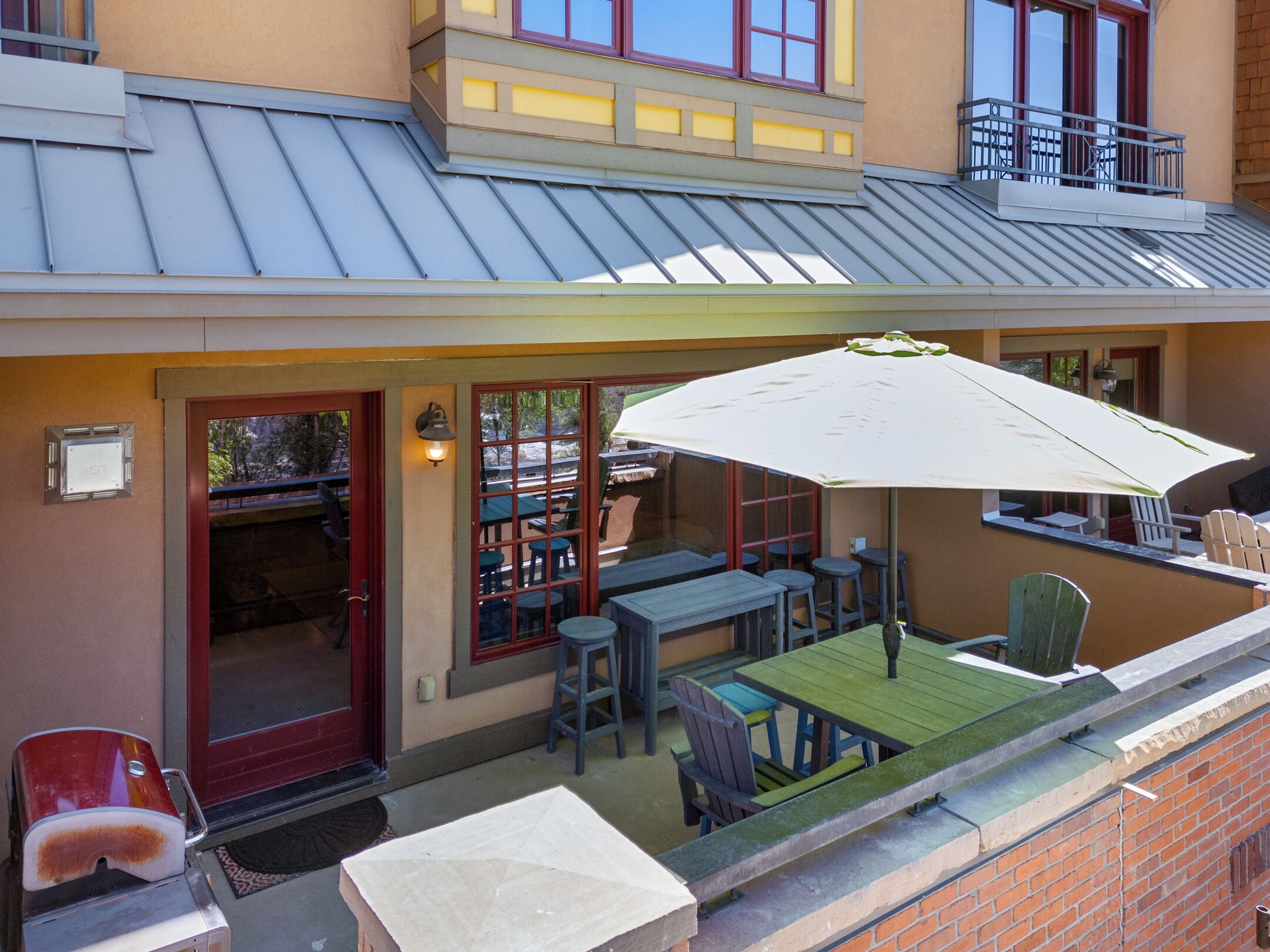 Eine Terrasse mit Sitzgelegenheiten im Freien, einem Tisch und einem großen Sonnenschirm.