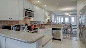 A modern kitchen with white cabinetry, stainless steel appliances, and a granite countertop. - Beachfront at Pointe West. Walk to the beach and the club all just steps away! (Galveston)