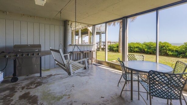 Un patio couvert équipé d’un barbecue, de chaises suspendues et d’une table avec des chaises.
