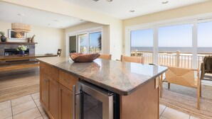 Una cocina moderna con encimera de granito, armarios de madera y lavavajillas integrado. Cuenta con un amplio ventanal con vistas al océano.