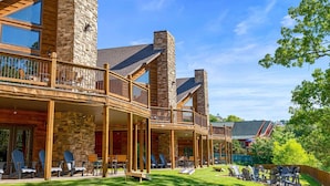 A log cabin with a stone tower, wooden balconies, and outdoor seating.