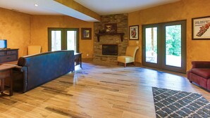 A spacious living room with a stone fireplace, large windows, and a cozy seating area.