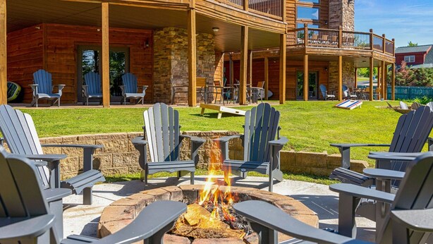 A wooden lodge with a fire pit surrounded by Adirondack chairs.