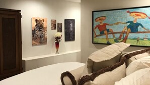 Une chambre avec un grand lit, une armoire en bois et des œuvres d’art accrochées aux murs.