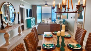 A dining area with a view of the ocean, a chandelier, and a buffet table set with plates and candles.
