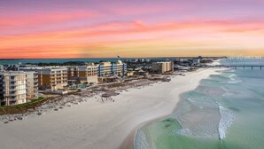 A coastal hotel with multiple buildings, a beach, and a pier.