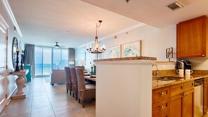 A spacious kitchen with a central island, wooden cabinets, and a dining area with wicker chairs.