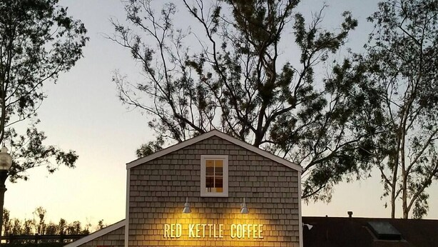 Un pequeño edificio de ladrillo con un letrero que dice 'Red Kettle Coffee'.