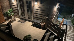 Un espacio al aire libre techado con piso de madera, plantas en macetas y un banco.