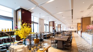 Un restaurant spacieux avec de hauts plafonds, de grandes fenêtres et différents types d’aménagements pour s’asseoir.