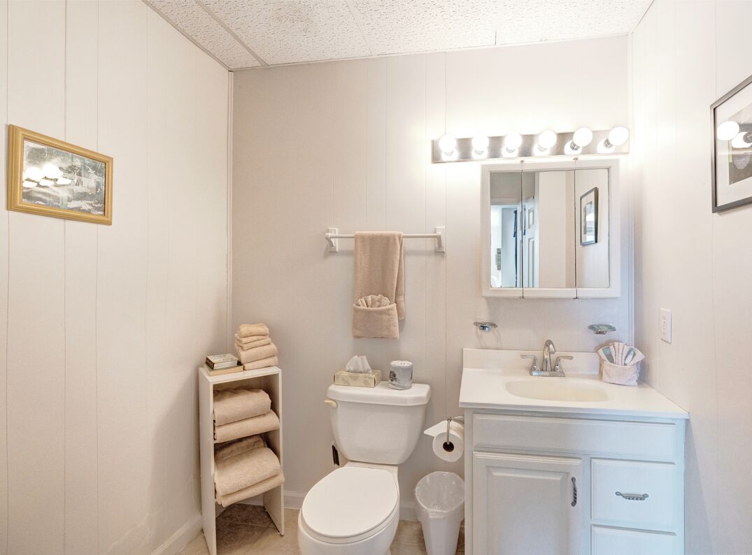 Un baño con inodoro, lavamanos, tocador y un espejo con luces.