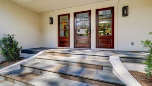 Une maison avec un escalier en pierre menant à une porte d’entrée dotée de panneaux de verre et d’un cadre en bois.