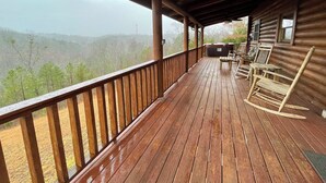 A wooden deck with a view of a forested mountain range.