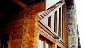 A log cabin with a stone exterior, large windows, and a wooden deck.