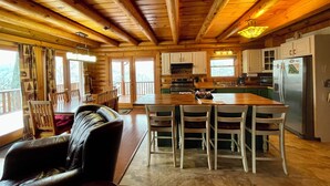 A wooden cabin interior with a dining area, kitchen, and a large island.