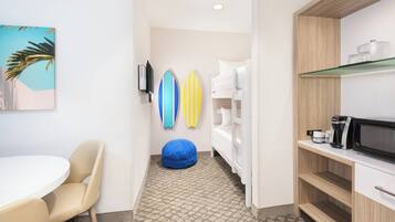 A room with a round table, a blue bean bag, a white bunk bed, and surfboards on the wall.
