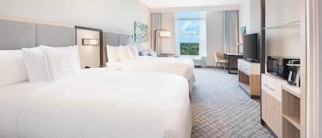 A hotel room with a large bed, a desk, a television, and a view of the outdoors.
