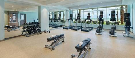 A spacious gym with treadmills, elliptical machines, and weight benches.