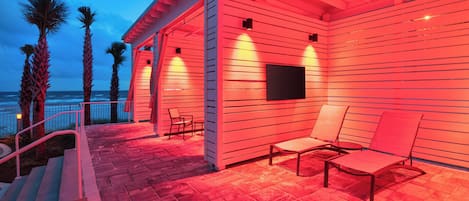 Un área de patio al aire libre con piscina, sillas de descanso y una pantalla de televisión.