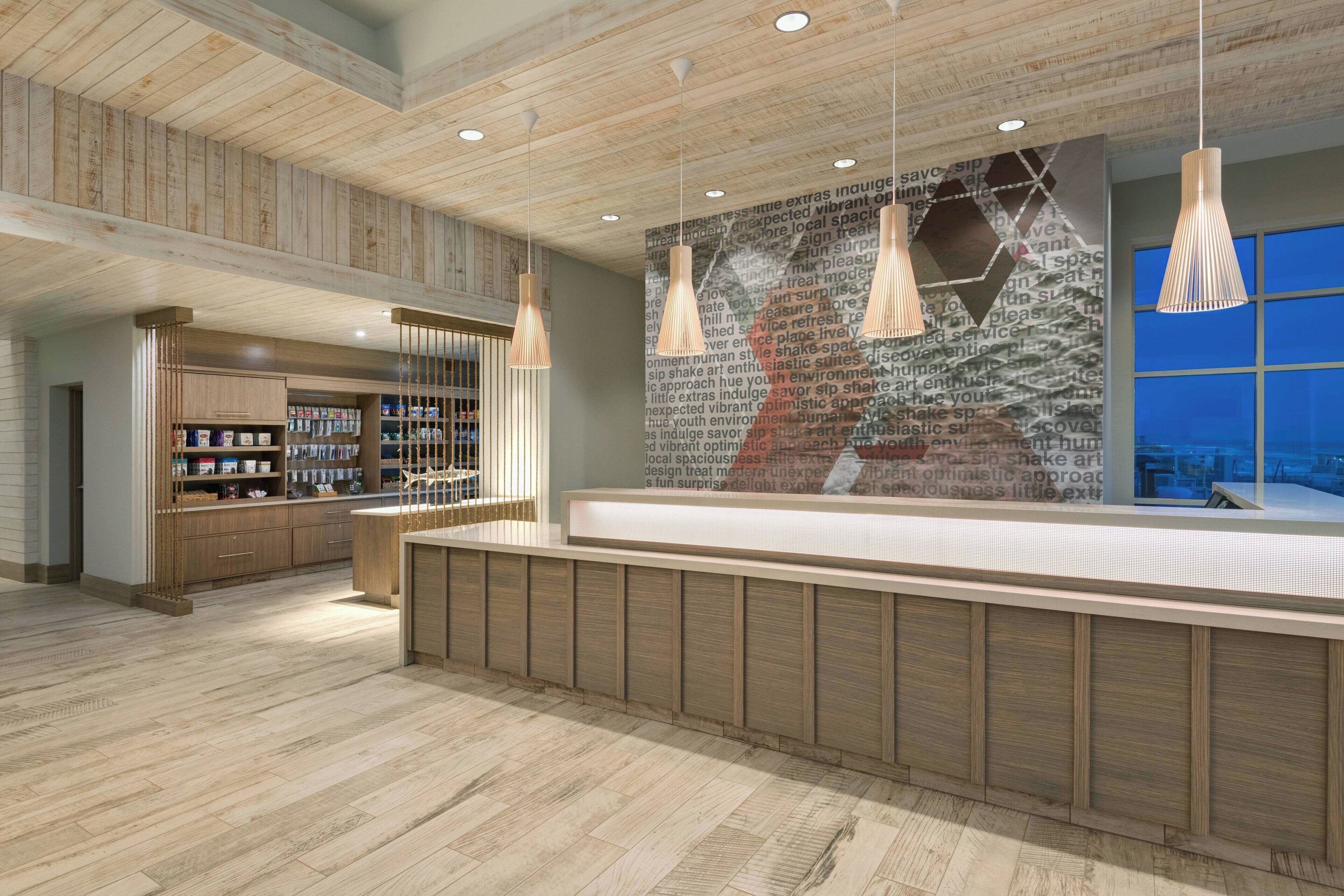 A modern reception area with wooden panel ceilings, a reception desk, and pendant lighting.