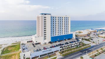 Un hotel con estacionamiento, vista al mar y un edificio grande de varios pisos.