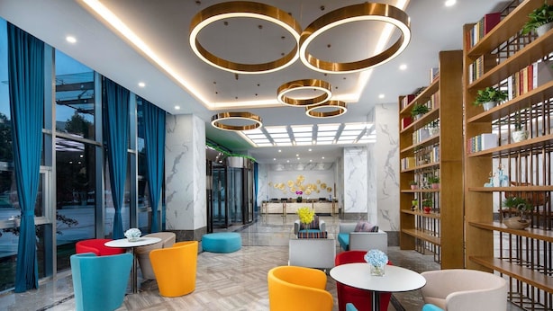 Un interior moderno con suelo de mármol, asientos coloridos, una mesa central y una estantería.