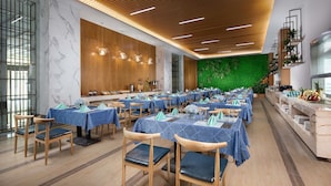 Un comedor amplio con varias mesas, sillas de madera y una pared verde.