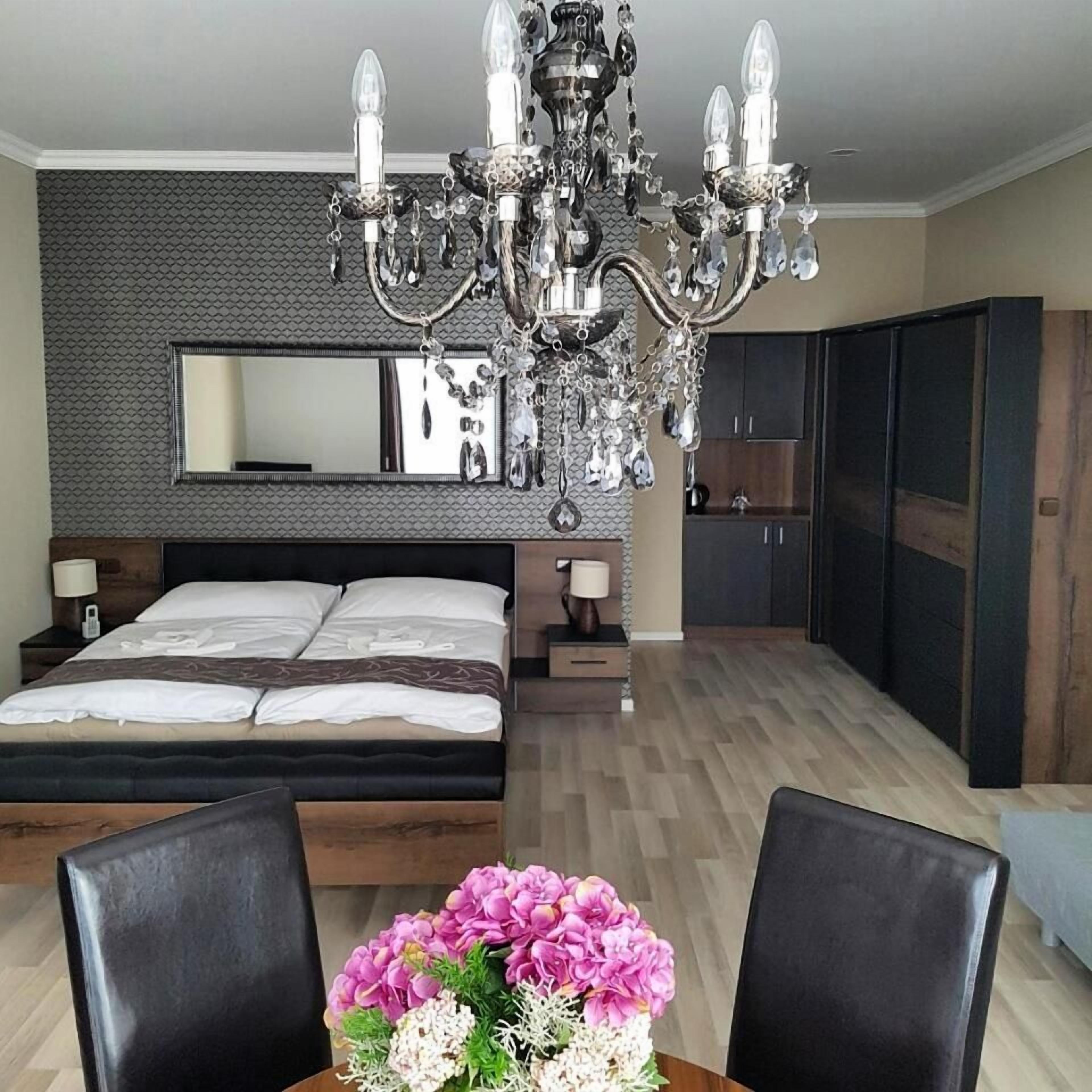 Ein modernes Schlafzimmer mit einem großen Bett, einer Chandelier, einem Schminktisch und einem Spiegel.