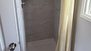 A shower area with a glass door, a showerhead, and a curtain. - Palms Motel (Emeryville)