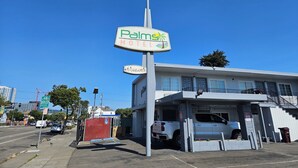 A motel named "Palms Motel" with a signboard, a gated parking area, and a building with a balcony. - Palms Motel (Emeryville)