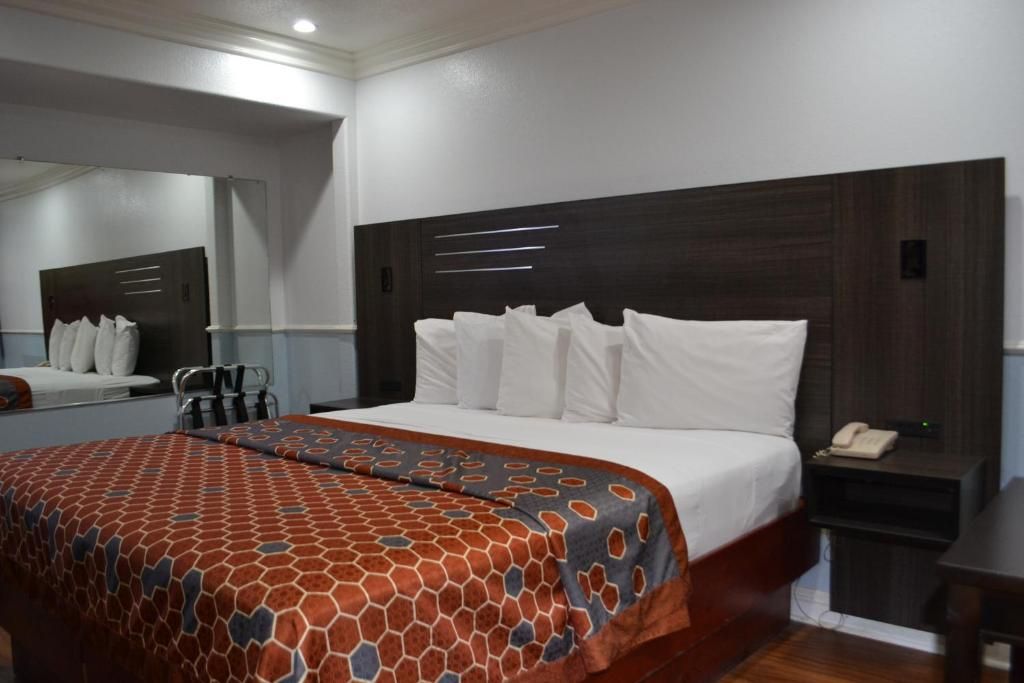 Una habitación de hotel con una cama grande, una mesita de noche con un teléfono y un espejo en la pared.