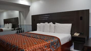 Una habitación de hotel con una cama grande, una mesita de noche con un teléfono y un espejo en la pared.