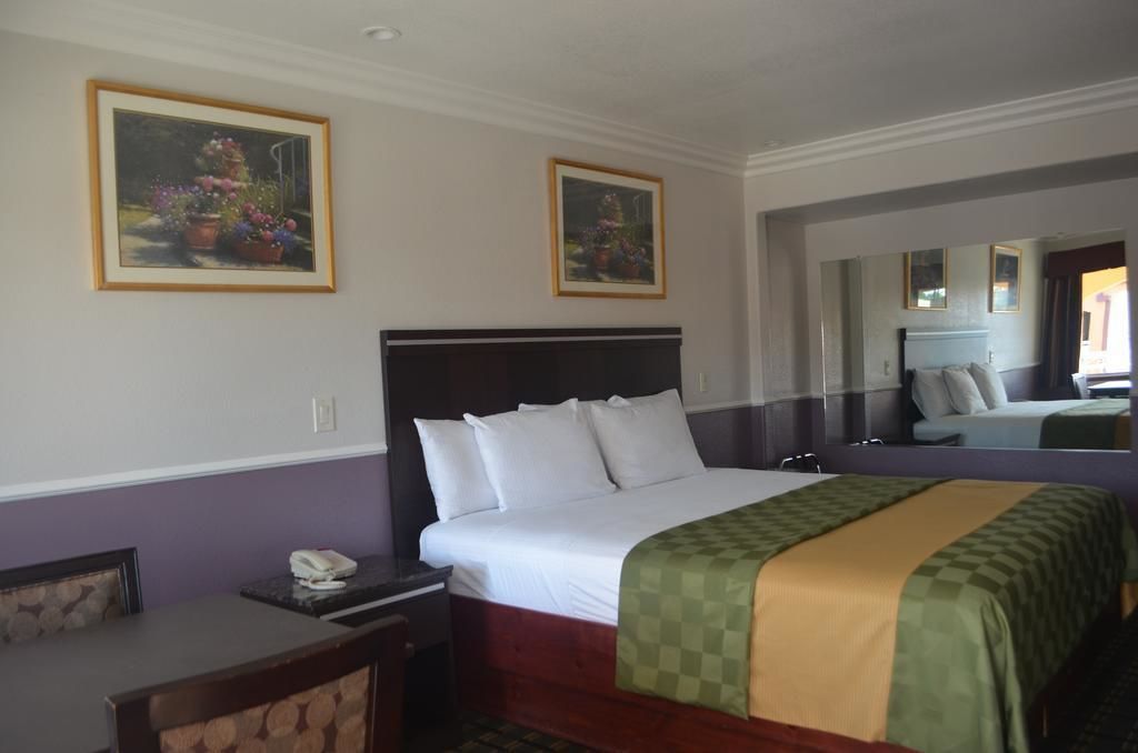 Una camera d'albergo con un letto grande, una scrivania e due quadri floreali appesi al muro.