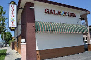 A Galaxy Inn building with a sign, a covered walkway, and a street view.