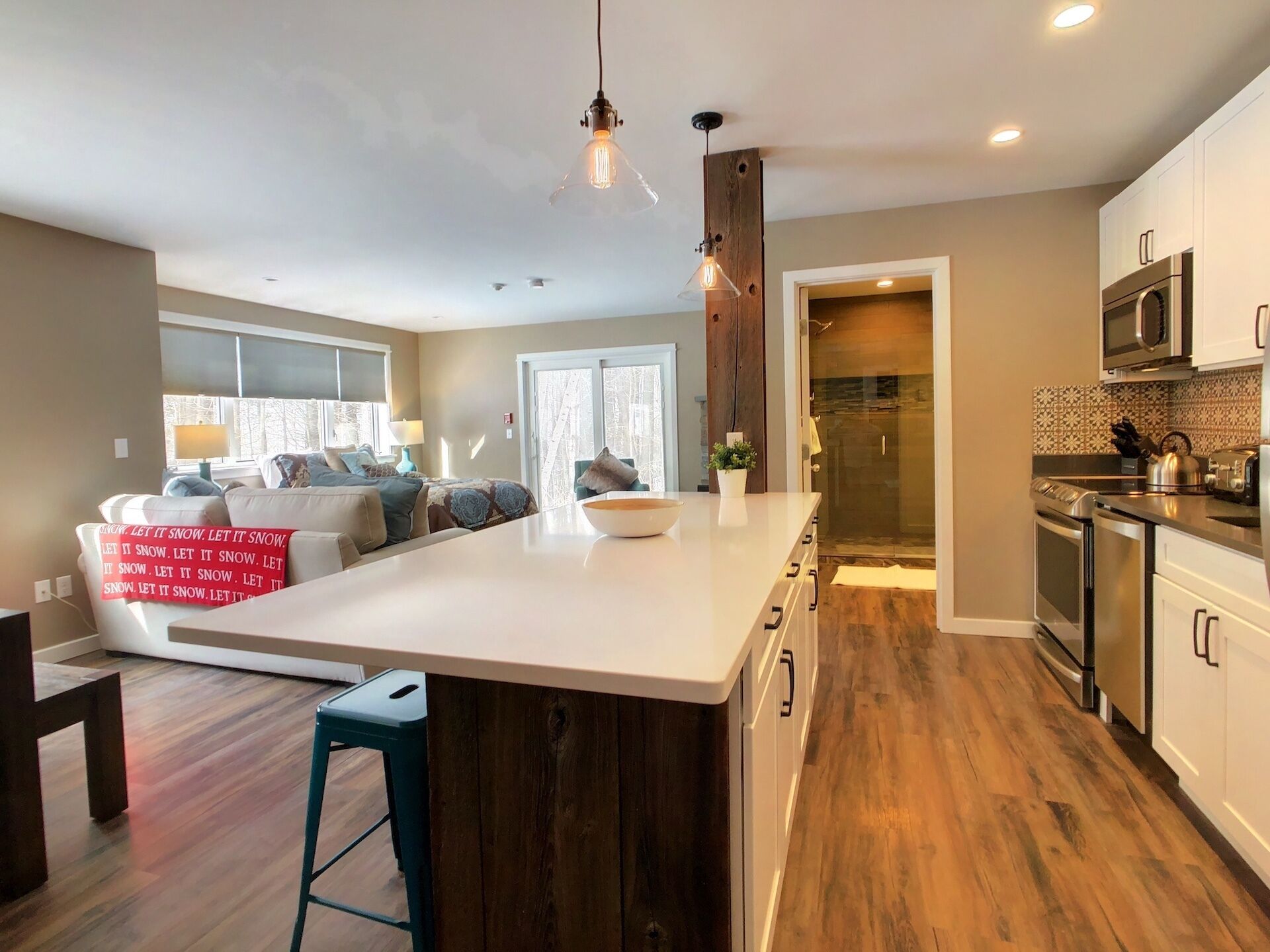 Een moderne keuken met een groot eiland, houten vloeren en witte kasten.