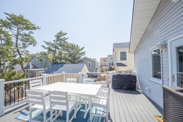 Una terraza con mesa y sillas, rodeada por una valla de madera, con vistas a una zona residencial con casas.