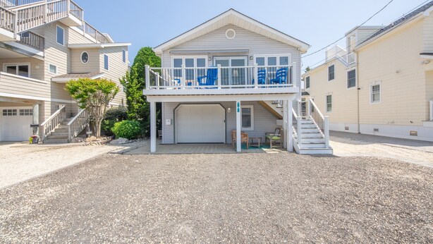 A two-story house with a covered front porch, a garage, and a staircase leading to the upper level. - Enjoy Family Memories - Great Outdoor Decks And Backyard; A Few Houses To Beach (Surf City)