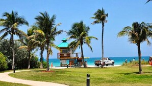 A beachside view with a lifeguard tower, palm trees, and a clear blue sky. - Beautiful/Spacious Ocean Reserve Sunny Isles Beach #STR-02481 (Sunny Isles Beach)