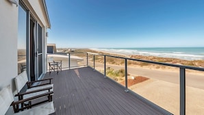 Un balcon avec vue sur la plage, une table et des chaises.